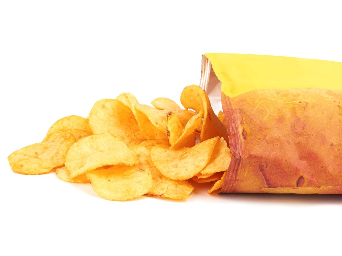 Open bag of crisps with its contents spilling out onto white