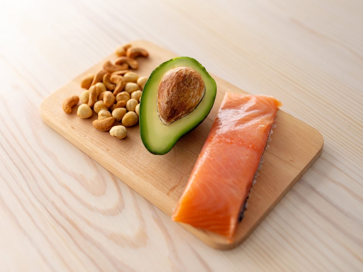 Salmon, avocado and nuts on a wooden board
