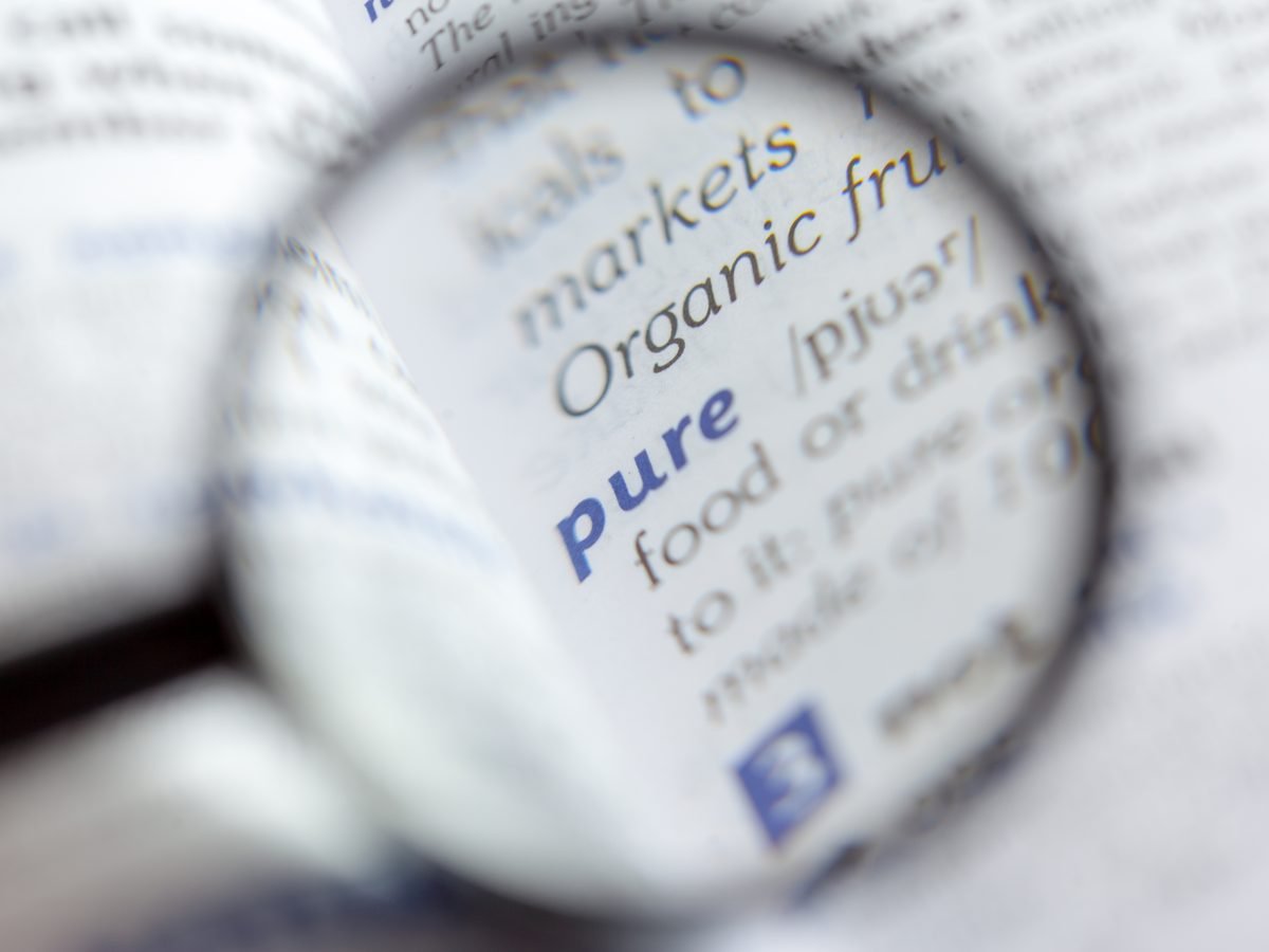 Magnifying glass enlarging the word pure in small printed text
