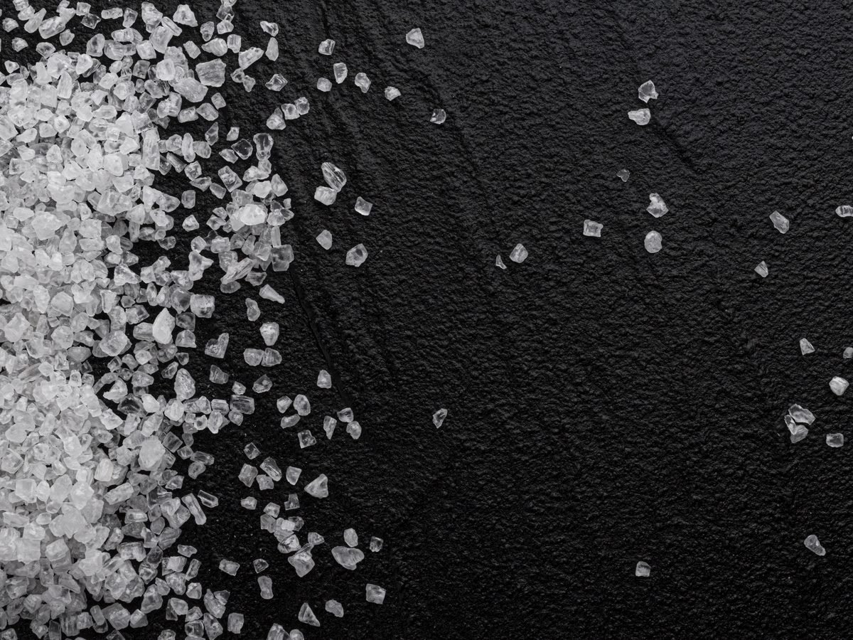 Coarse salt crystals scattered across a black stone surface