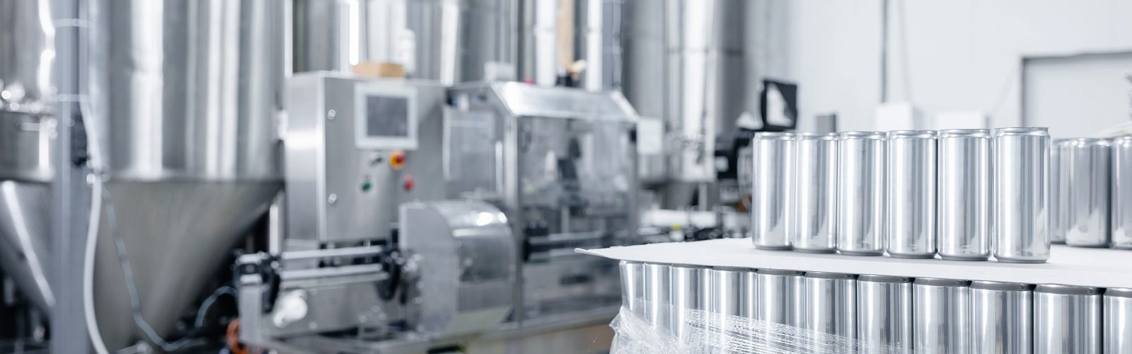 Stainless fermentation tanks and a canning line inside a modern beverage plant
